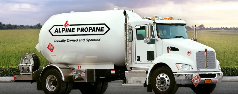 An Alpine Propane truck sitting in front of a field.